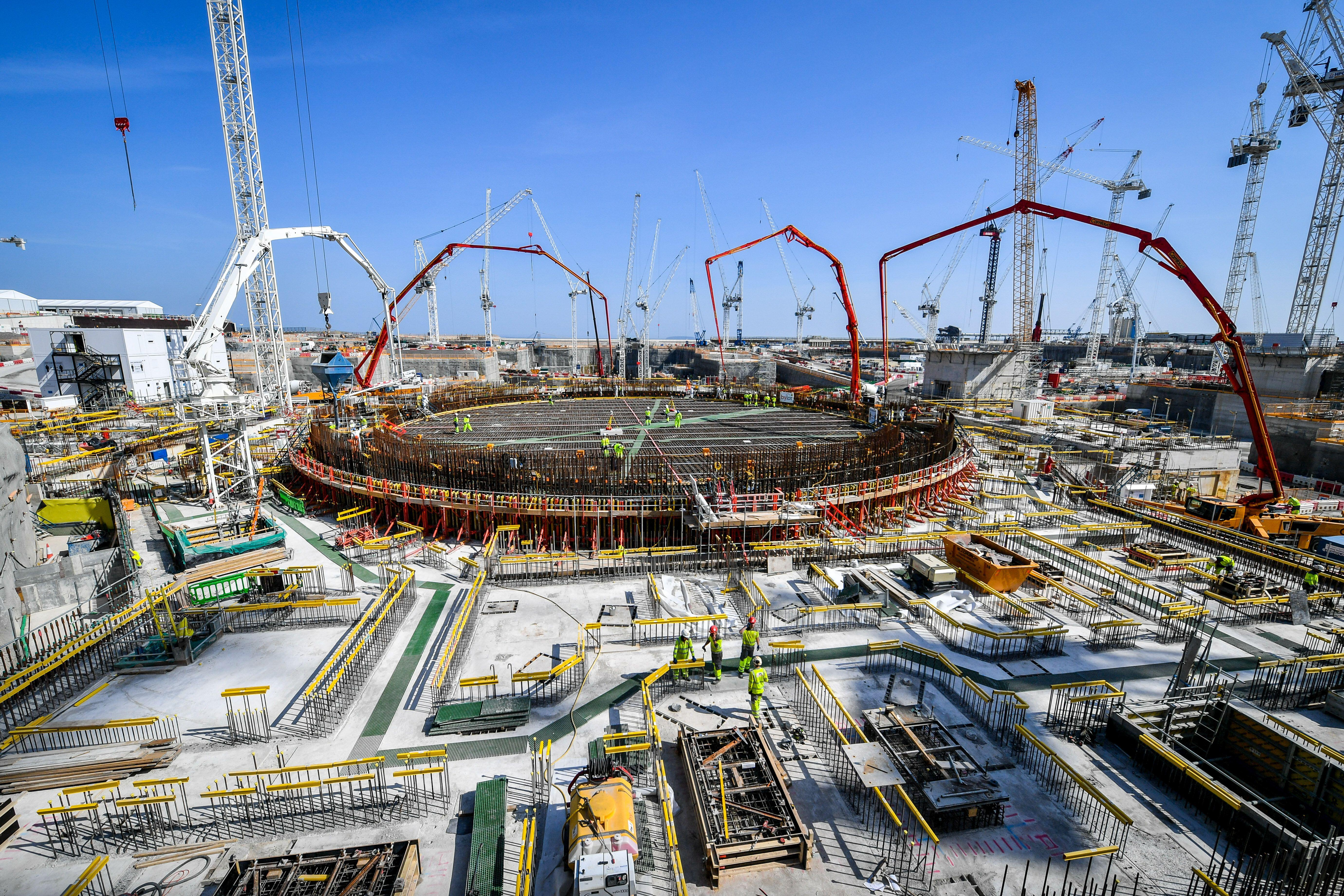 Construction workers and huge concrete pumping arms fill the reinforced steel base of the unit 2 nuclear reactor at Hinkley Point C near Bridgwater in Somerset, Europe's largest building site